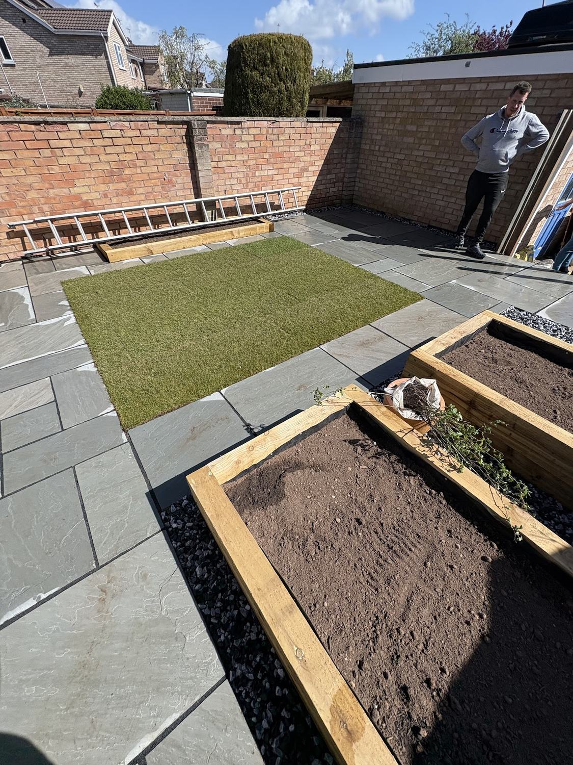 An Indian sandstone patio with a new lawn and sleeper raised beds