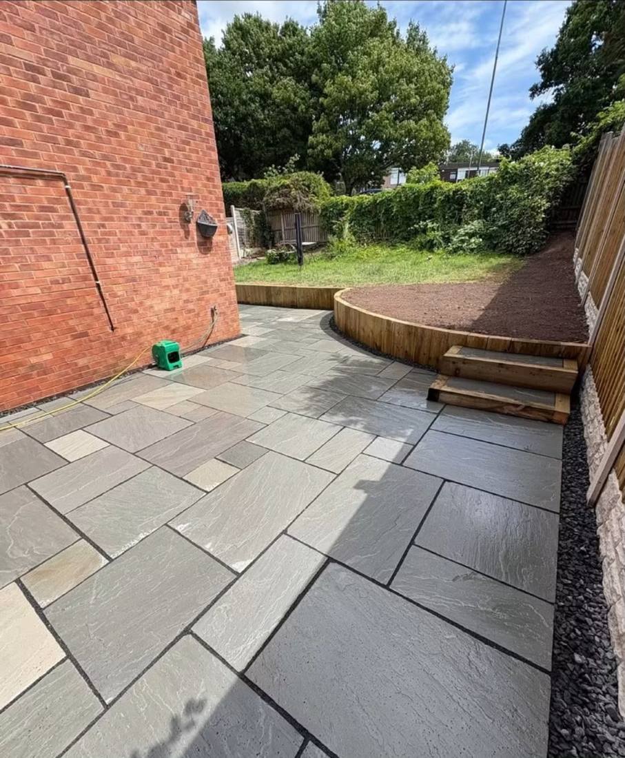 Wide Indian sandstone paving running down the side of a red brick house