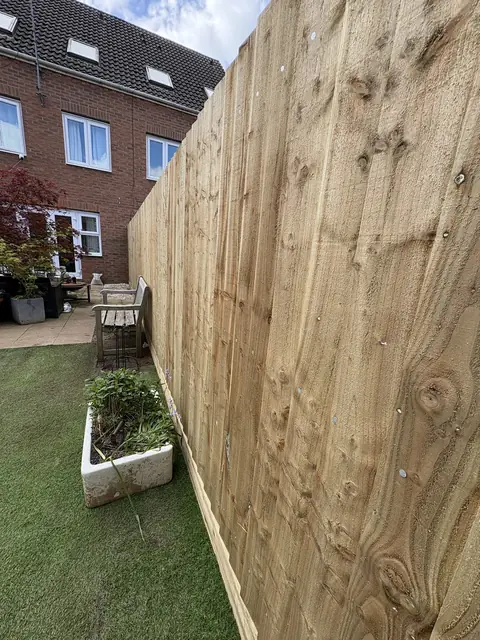 A tall closeboard fence run built along a garden boundary