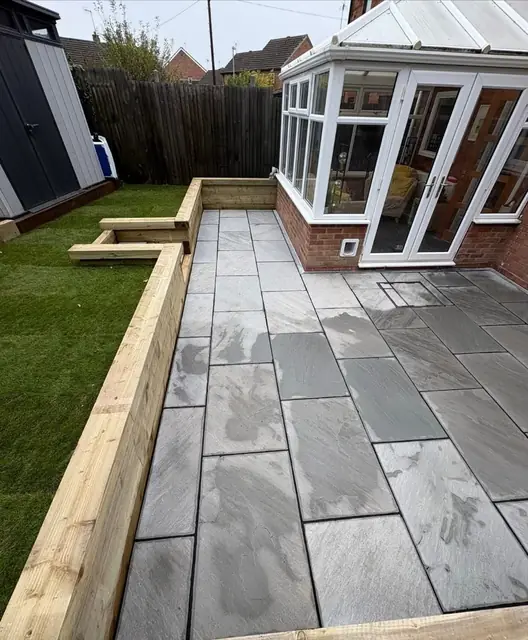 Paving and a lawn finished around a conservatory with sleeper edging