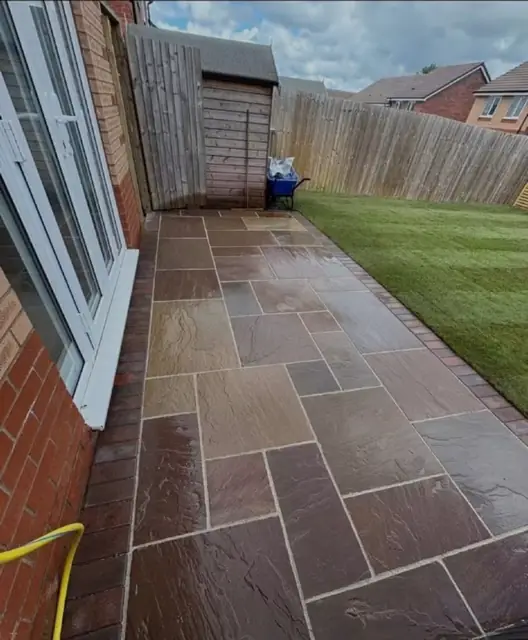 A slab path running down a narrow side passage beside a fence