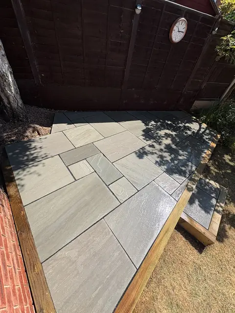 A finished grey sandstone patio with black edging, seen from above