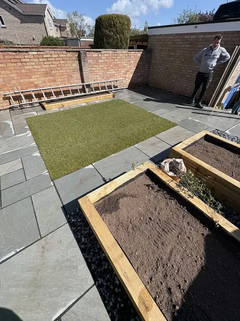 An Indian sandstone patio with a new lawn and sleeper raised beds