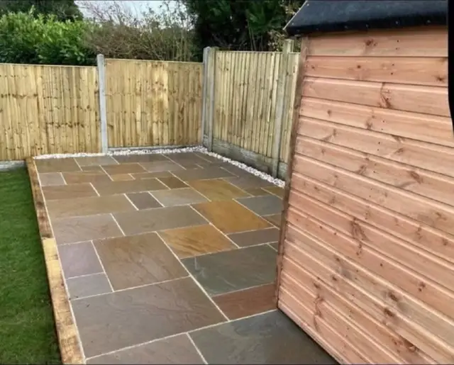 A sandstone patio finished into the corner of two new fence runs