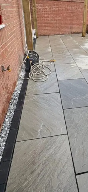 Indian sandstone slabs laid with a slate border against a brick wall